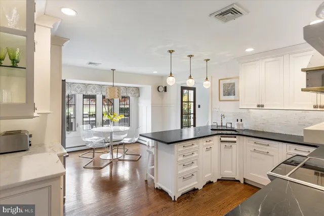 a kitchen with stainless steel appliances granite countertop a stove a refrigerator a oven a dining table and chairs with wooden floor