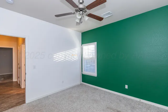 a view of an empty room with window and a ceiling fan