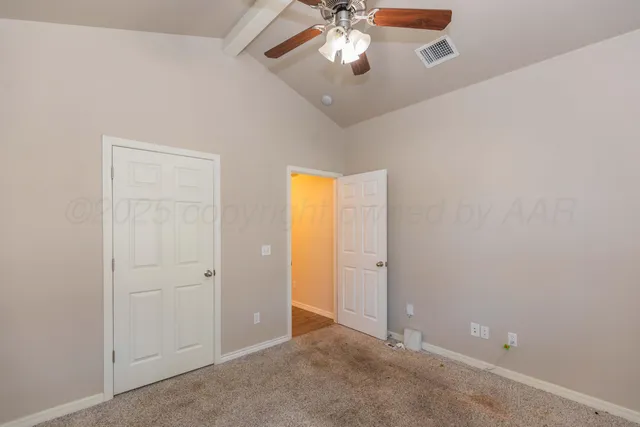 an empty room with a chandelier fan and closet