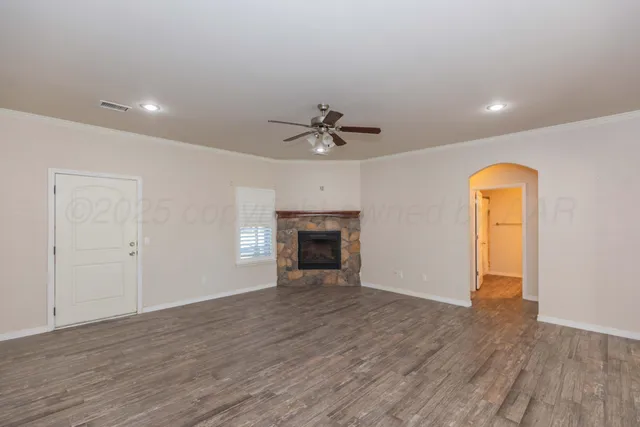 an empty room with wooden floor and a ceiling fan
