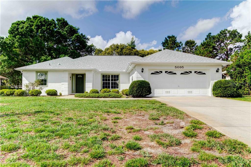 5095 Winterville Road Spring Hill, FL 34608 - Photo 1 of 1 a view of a white house with a yard plants and large tree