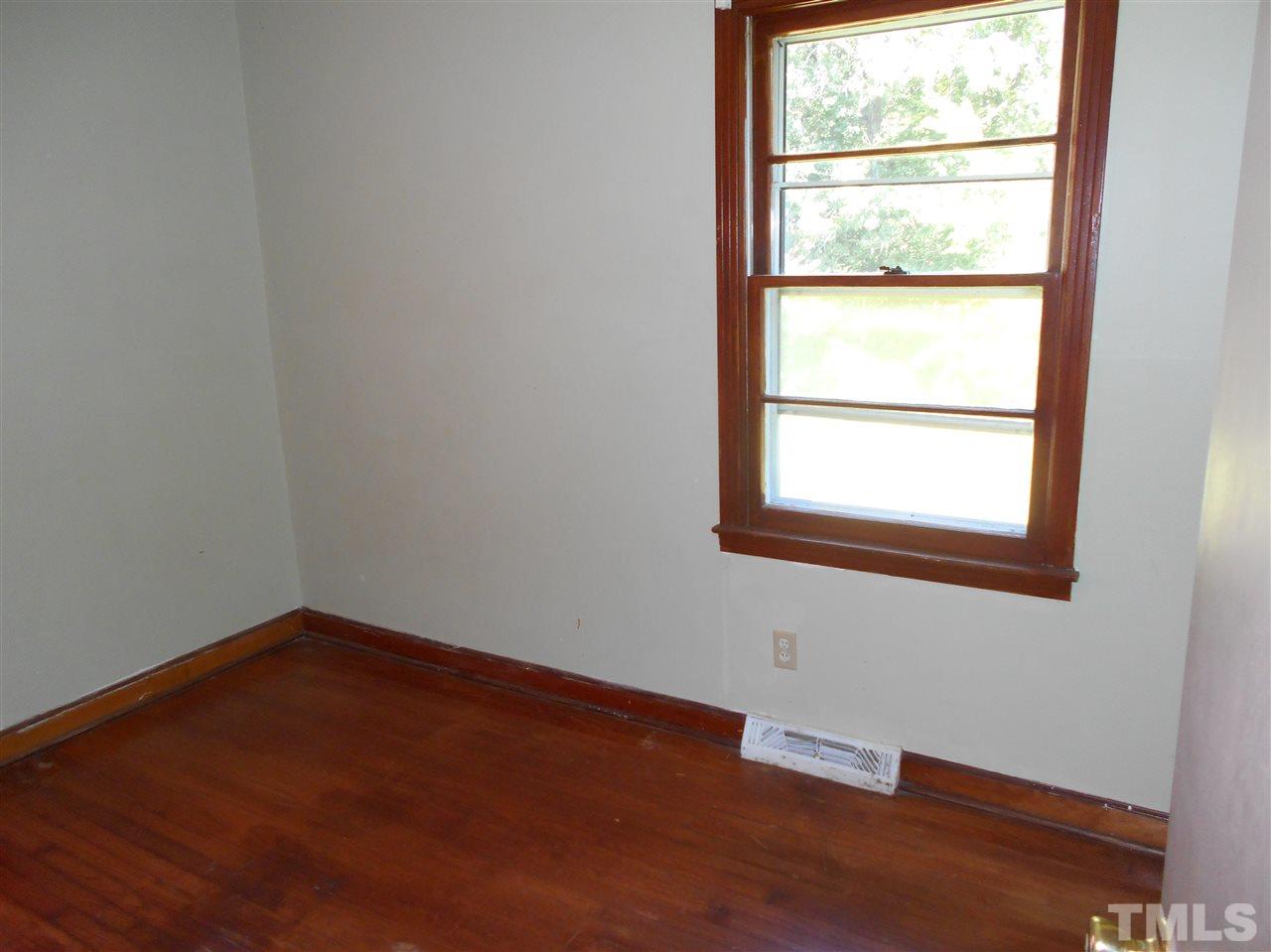 910 Mackfieldson Road Roxboro, NC 27574 - Photo 5 of 10 a view of an empty room with wooden floor and a window
