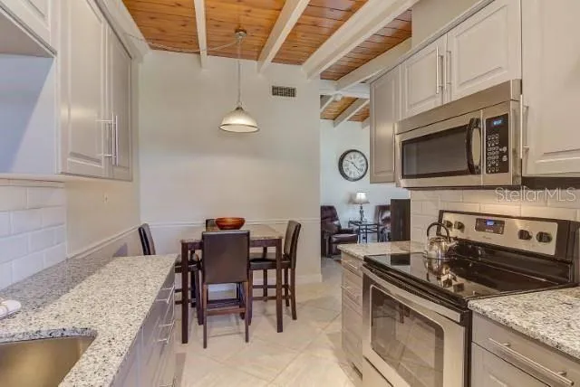 a kitchen with stainless steel appliances granite countertop a stove top oven a sink a dining table and chairs with wooden floor