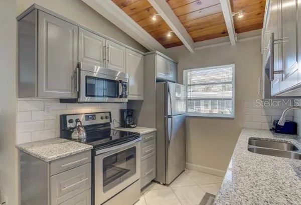 a kitchen with granite countertop a stove sink and microwave