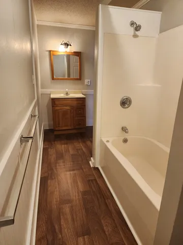 a bathroom with a tub a sink and wooden floor
