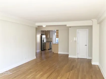 a view of a hallway with wooden floor and a bathroom