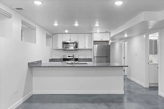 a kitchen with stainless steel appliances granite countertop a sink a stove a refrigerator a center island and cabinets