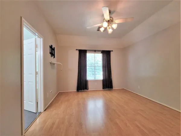 a view of an empty room with a window and wooden floor