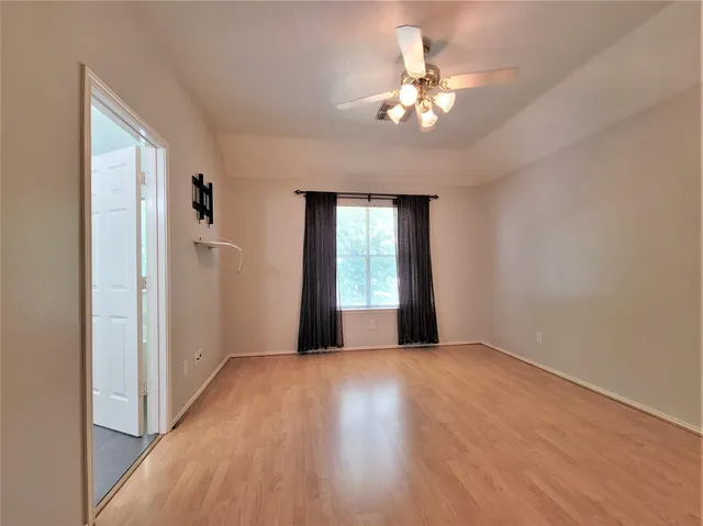 a view of an empty room with a window and wooden floor
