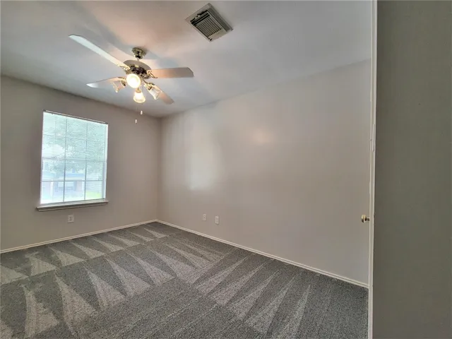 an empty room with a window and a fan