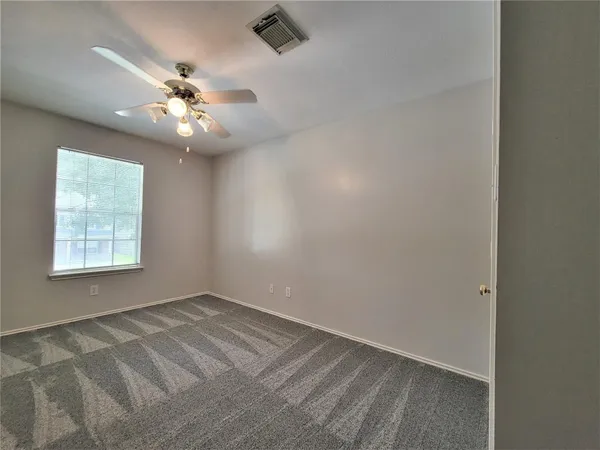 an empty room with a window and a fan