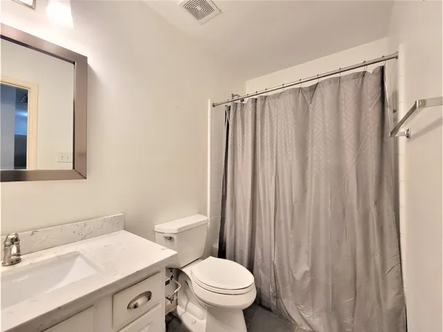 a bathroom with a sink a toilet a mirror and shower curtain