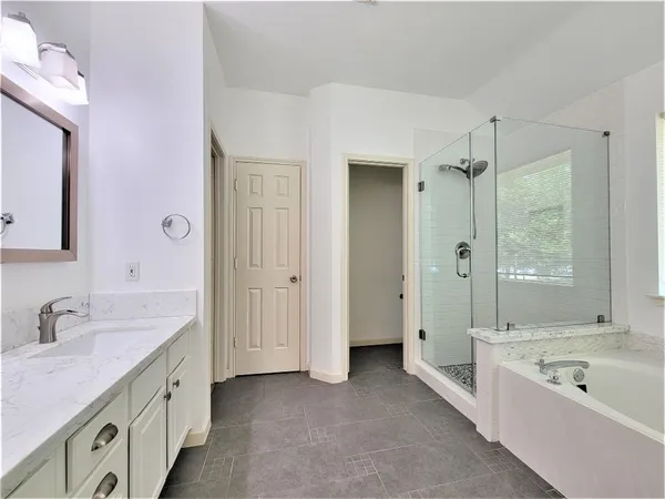a spacious bathroom with a granite countertop tub sink double vanity and a tub