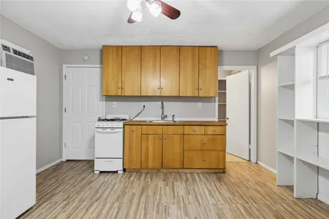 a kitchen with wooden floors and white stainless steel appliances
