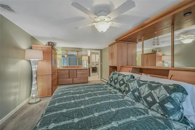 a spacious bedroom with a bed a dresser and a chandelier