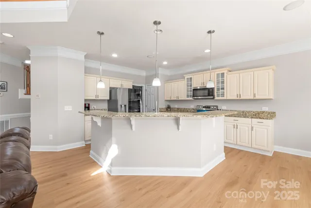 a view of kitchen with stainless steel appliances granite countertop a refrigerator a sink dishwasher a stove and white cabinets with wooden floor