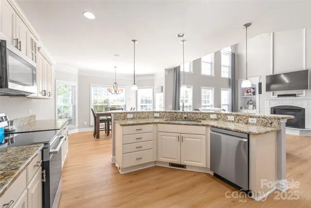 a kitchen with stainless steel appliances granite countertop a stove a sink dishwasher and a refrigerator with wooden floor