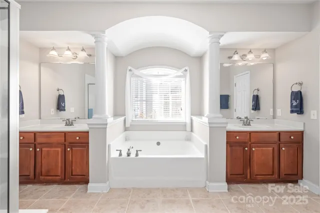 a spacious bathroom with a tub sink and mirror