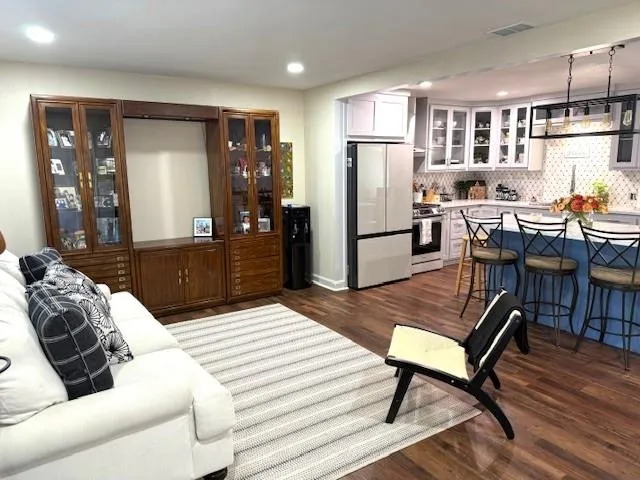a living room with stainless steel appliances furniture a dining table and kitchen view