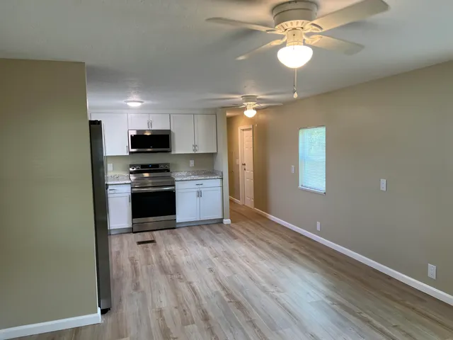 a view of an empty room with window and wooden floor