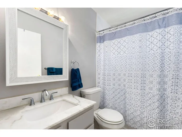 a bathroom with a granite countertop sink mirror vanity and toilet