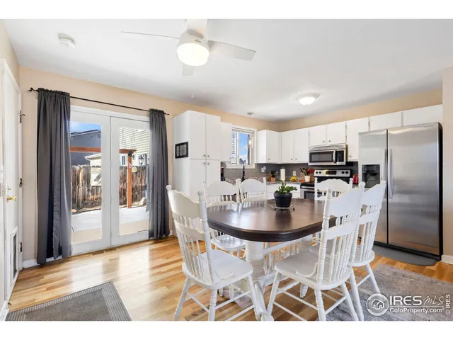 a kitchen with stainless steel appliances kitchen island granite countertop a dining table chairs and a refrigerator