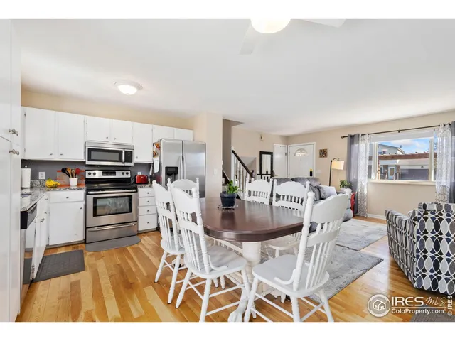 a kitchen with stainless steel appliances kitchen island granite countertop a refrigerator a stove a microwave oven with white cabinets and wooden floor