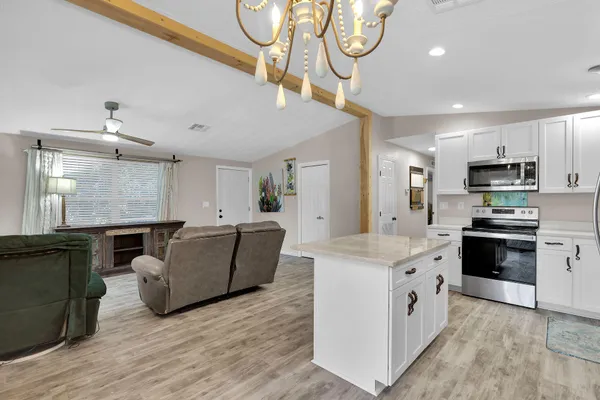 a kitchen with kitchen island granite countertop a stove top oven a sink a counter top space and cabinets