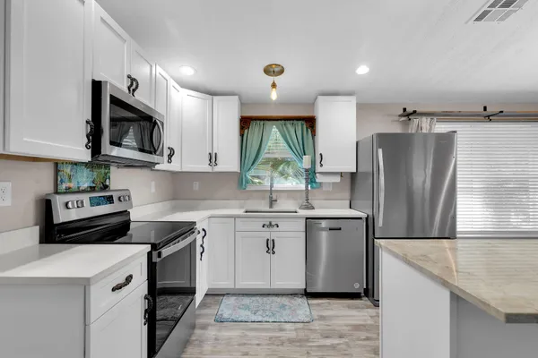 a kitchen with stainless steel appliances granite countertop a stove a sink dishwasher a refrigerator and a microwave