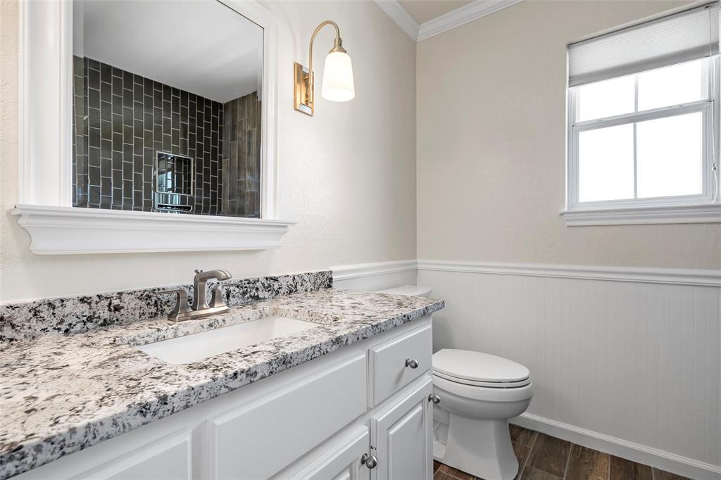5112 Old Caufield Ranch Road McGregor, TX 76657 - Photo 26 of 38 Full bath featuring dark wood-type flooring, vanity, crown molding, a wainscoted wall, and tiled shower