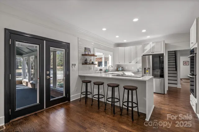 a kitchen with stainless steel appliances a table chairs refrigerator and cabinets