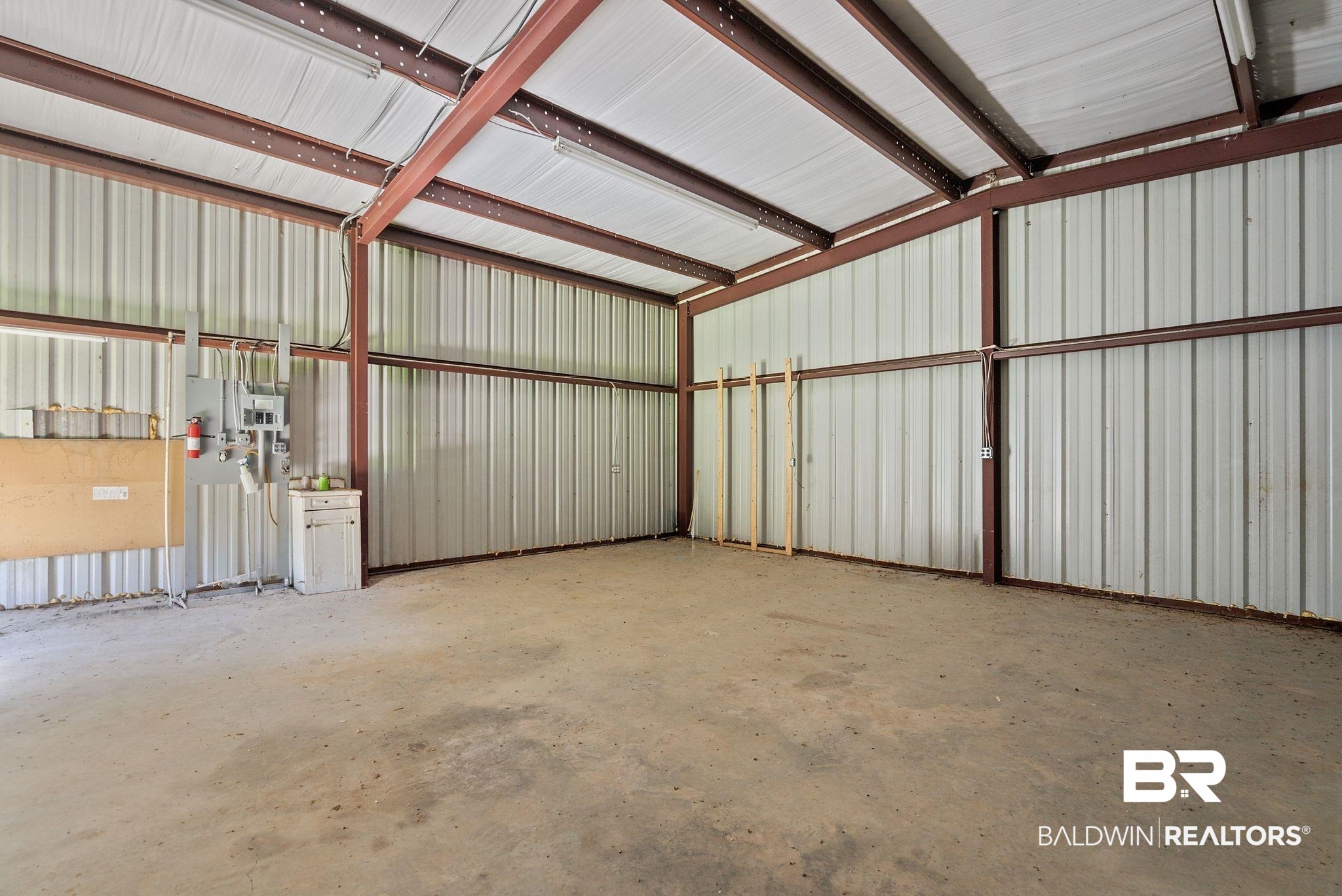 18318 Kendrick Road Robertsdale, AL 36567 - Photo 26 of 39 Spacious metal building interior featuring a concrete floor, exposed steel beam construction, corrugated metal walls, and overhead fluorescent lighting
