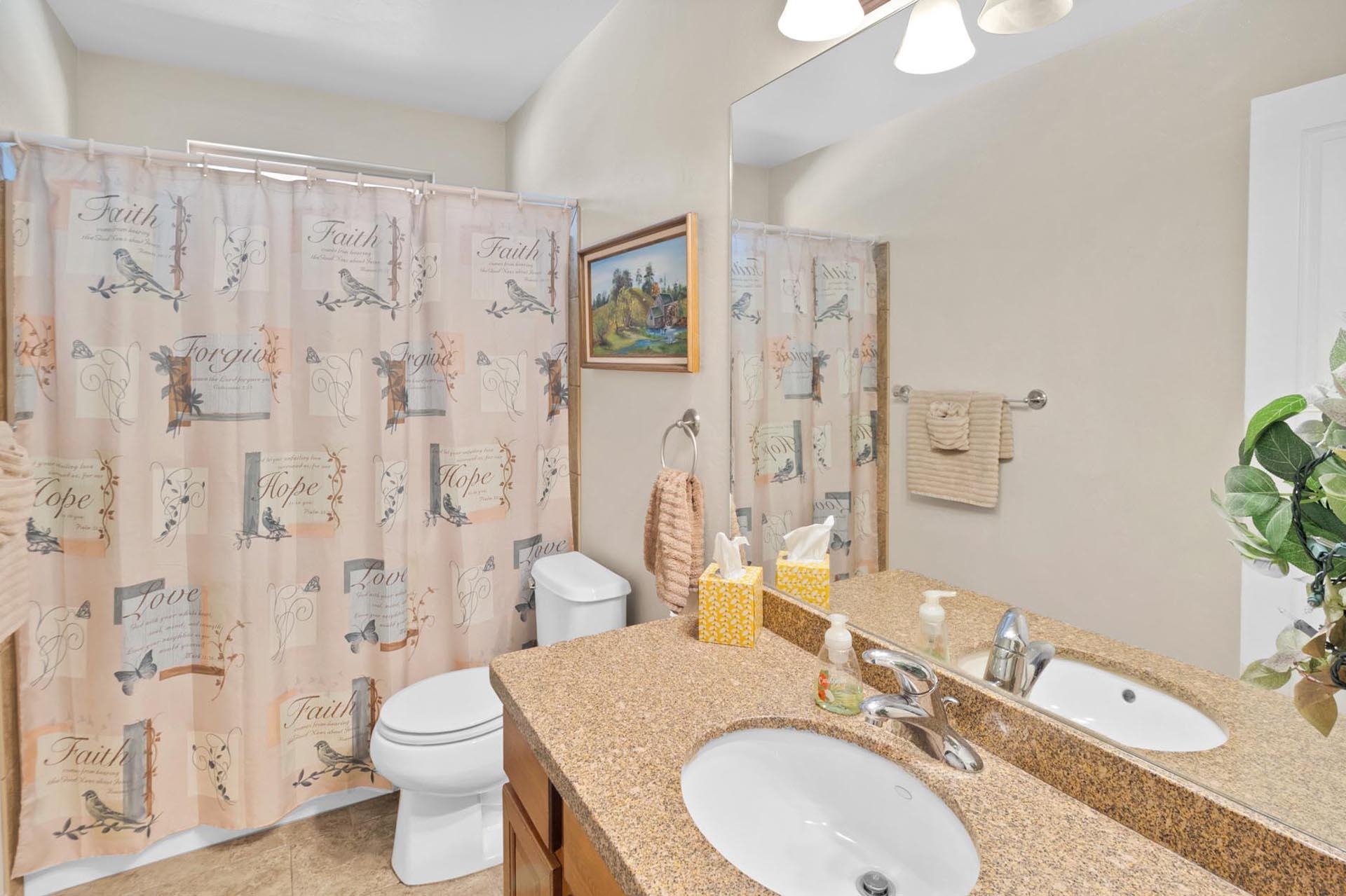 247 Mason Ridge Drive Grand Junction, CO 81503 - Photo 33 of 40 a bathroom with a granite countertop sink toilet a mirror and shower curtain
