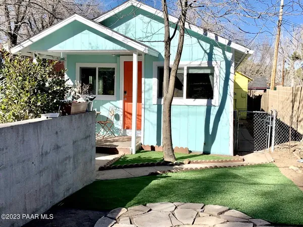 a view of a white house with a small yard and potted plants