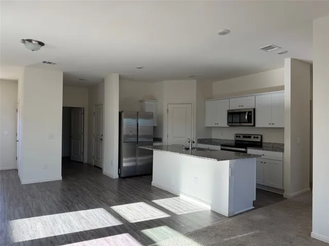 a kitchen with stainless steel appliances kitchen island granite countertop a refrigerator and a stove top oven