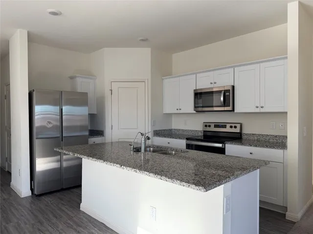 a kitchen with stainless steel appliances granite countertop a sink a stove and a refrigerator