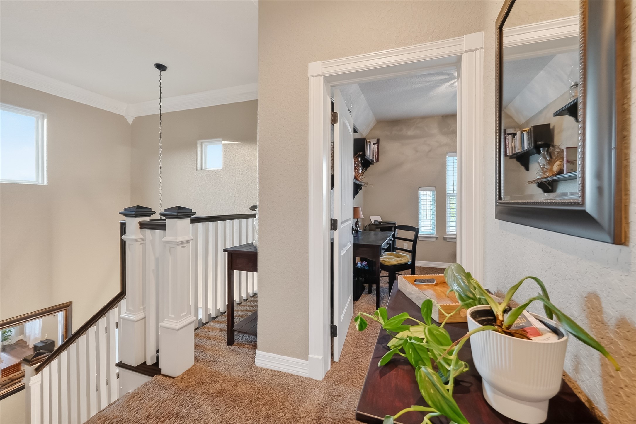 912 County Road 340 Angleton, TX 77515 - Photo 21 of 50 This photo showcases a cozy upstairs hallway with carpeted flooring and white railings leading to an adjacent space with ample natural light from two windows.