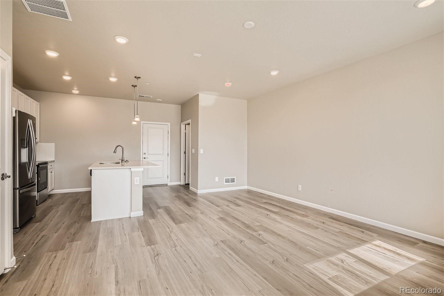 6700 Merseyside Lane Castle Pines, CO 80108 - Photo 5 of 28 a view of a kitchen with a sink and dishwasher a refrigerator with wooden floor