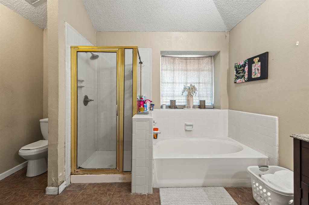 3717 Corn Valley Road Grand Prairie, TX 75052 - Photo 13 of 14 a bathroom with a white bath tub a toilet and a shower
