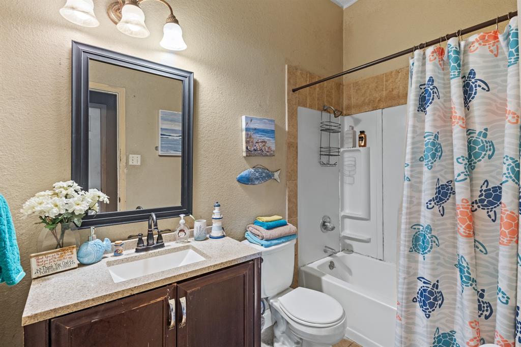 3717 Corn Valley Road Grand Prairie, TX 75052 - Photo 9 of 14 a bathroom with a granite countertop sink toilet a mirror a vanity and shower
