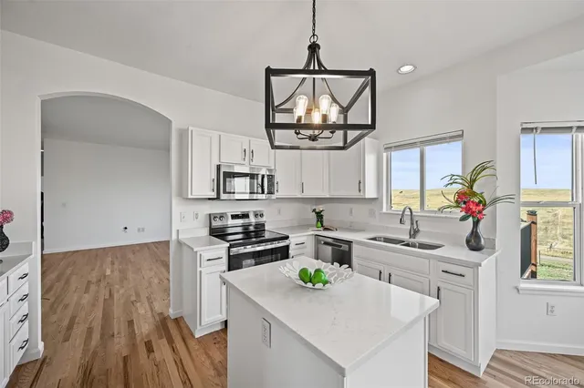 a kitchen with stainless steel appliances a sink stove and wooden floor