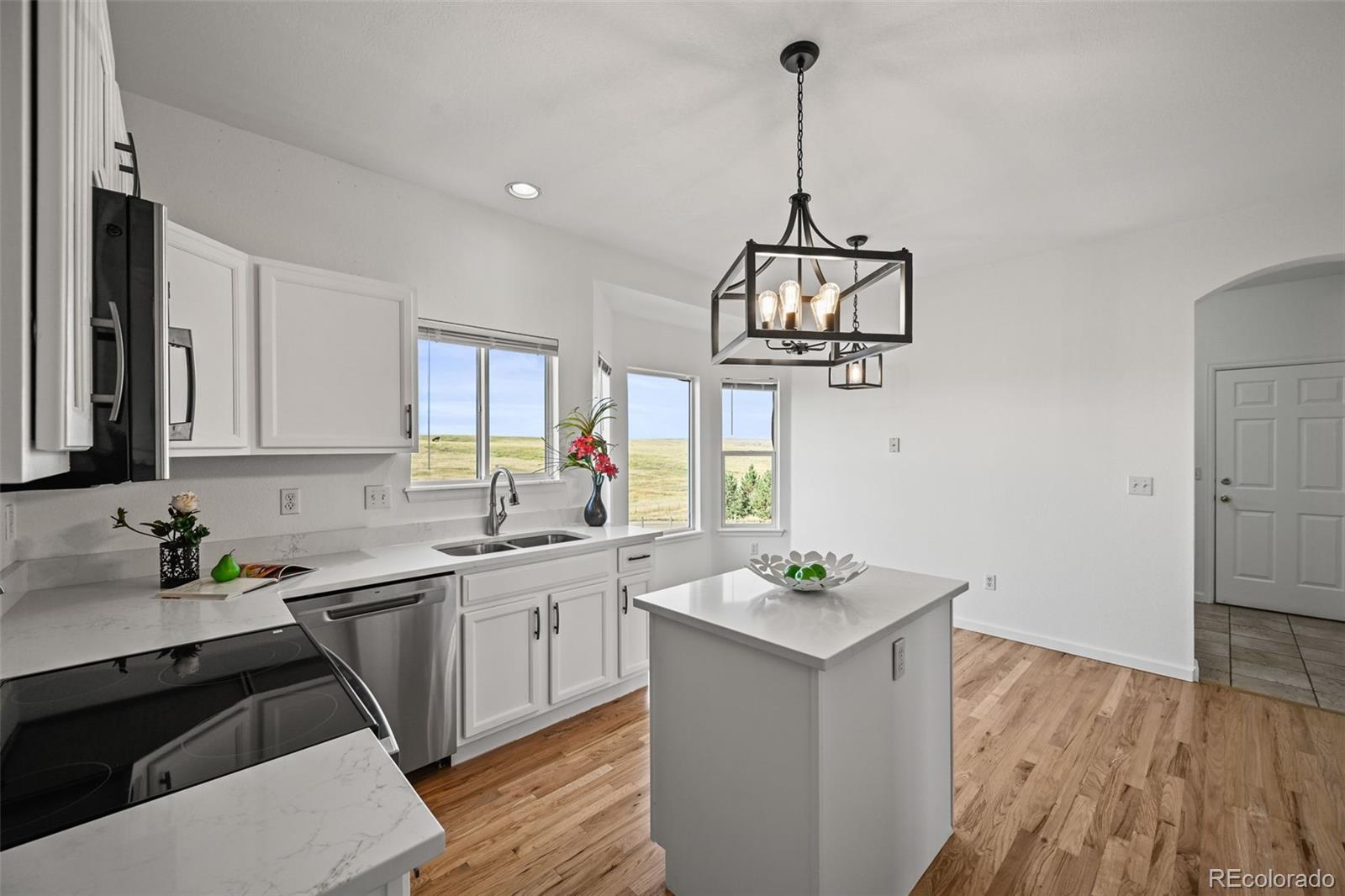 7498 Patrick Trail Elizabeth, CO 80107 - Photo 10 of 44 a kitchen with a sink dishwasher a stove a microwave oven with white cabinets and wooden floor