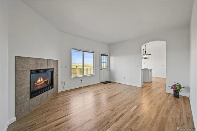 an empty room with windows fireplace and wooden floor
