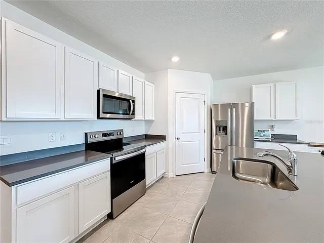 a view of kitchen with kitchen island stainless steel appliances refrigerator stove dining table and chairs