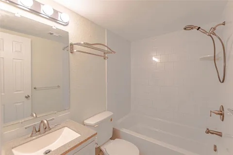 a bathroom with a granite countertop sink a toilet and shower