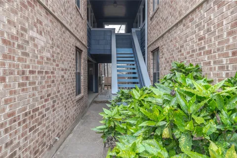 a pathway of a house with potted plants in front of door