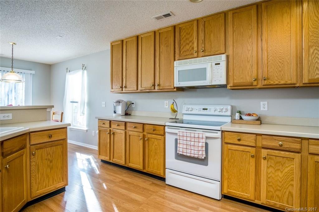 7474 Fallen Timber Lane Tega Cay, SC 29708 - Photo 14 of 24 a kitchen with stainless steel appliances granite countertop wooden cabinets a sink and dishwasher a stove with wooden floor