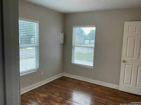 a view of an empty room with wooden floor and a window
