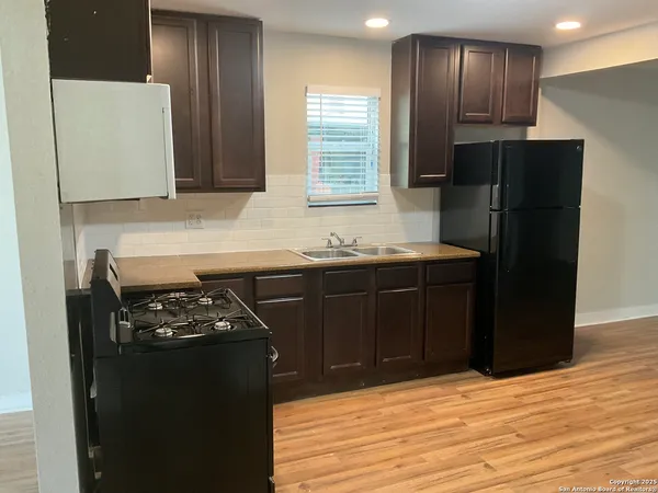 a kitchen with granite countertop stainless steel appliances a stove refrigerator and cabinets