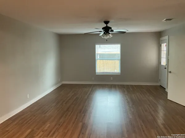 a view of an empty room with wooden floor and a window